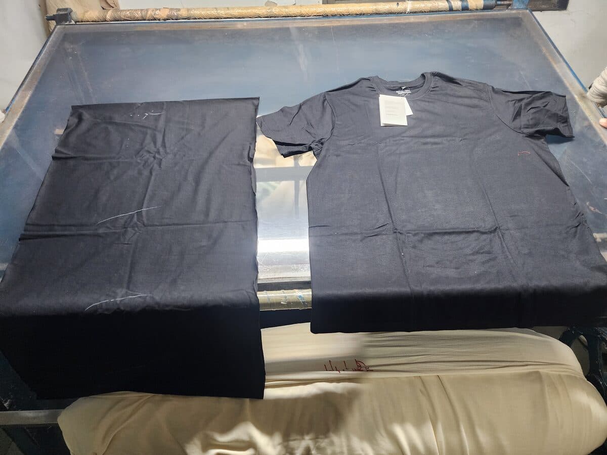 Finished Boring Label Supima cotton t-shirt on inspection table alongside cut fabric swatch for final quality check